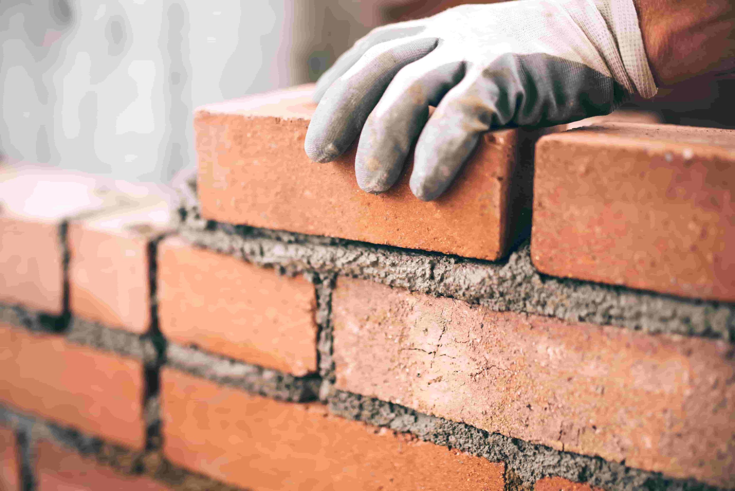 A close up of bricks being placed by a construction worker